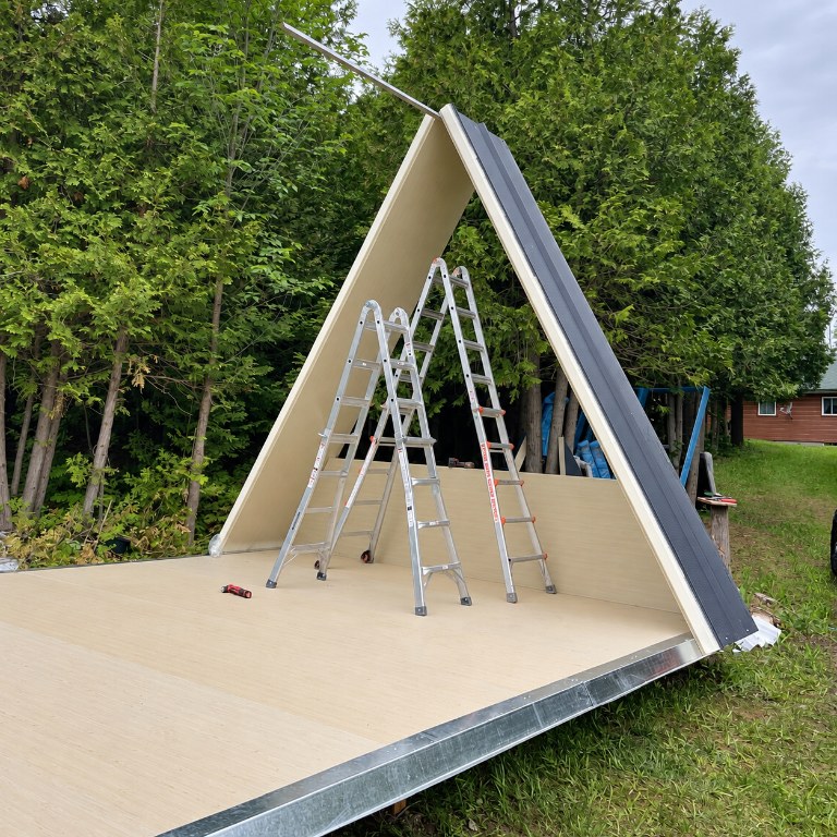 Interior view of an A-Frame cabin showing the continuous CENLUXE SIP panel structure forming roof and walls